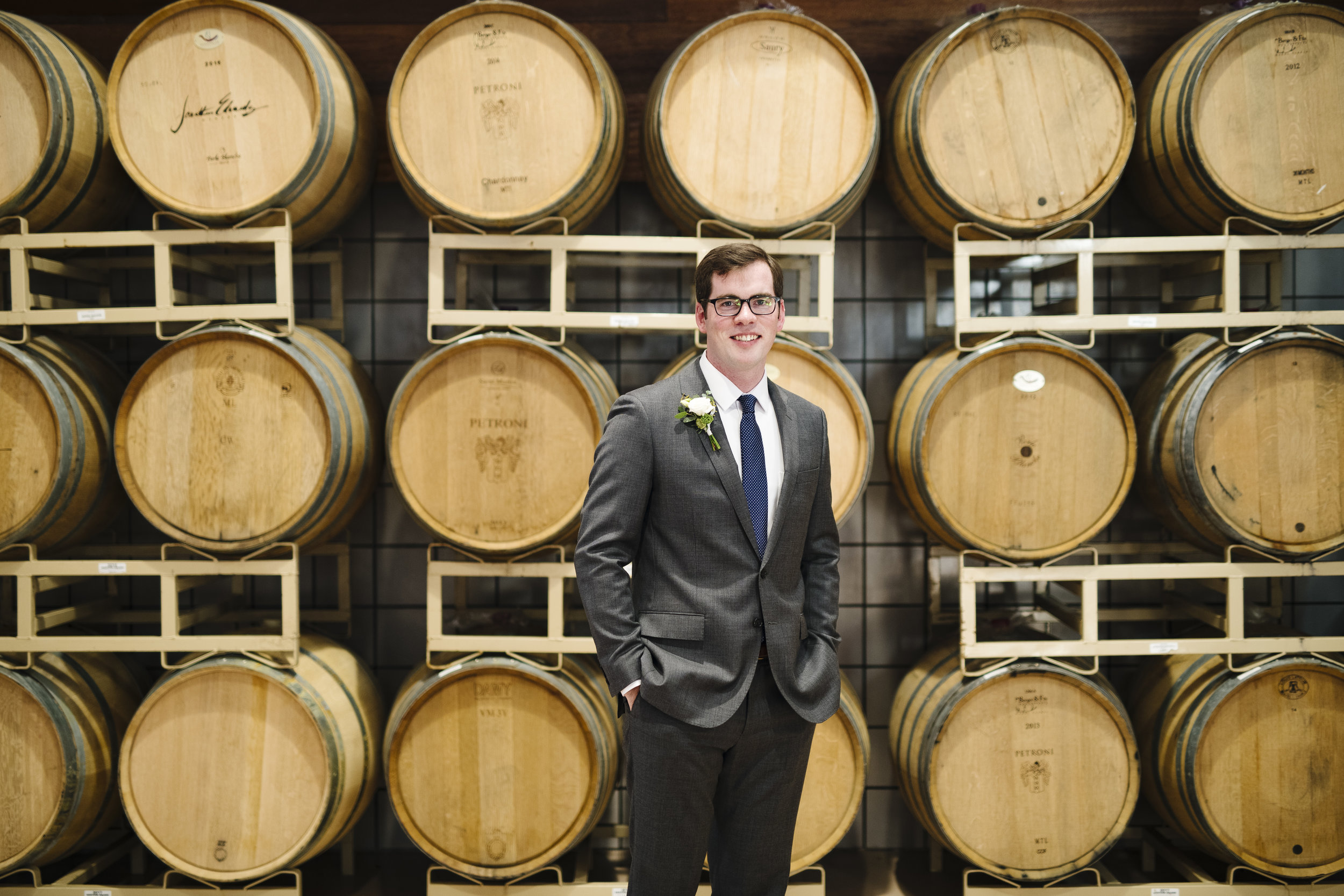 Groom photos in front of wine barrels at jonathan edwards winery - Pearl Weddings &amp; Events