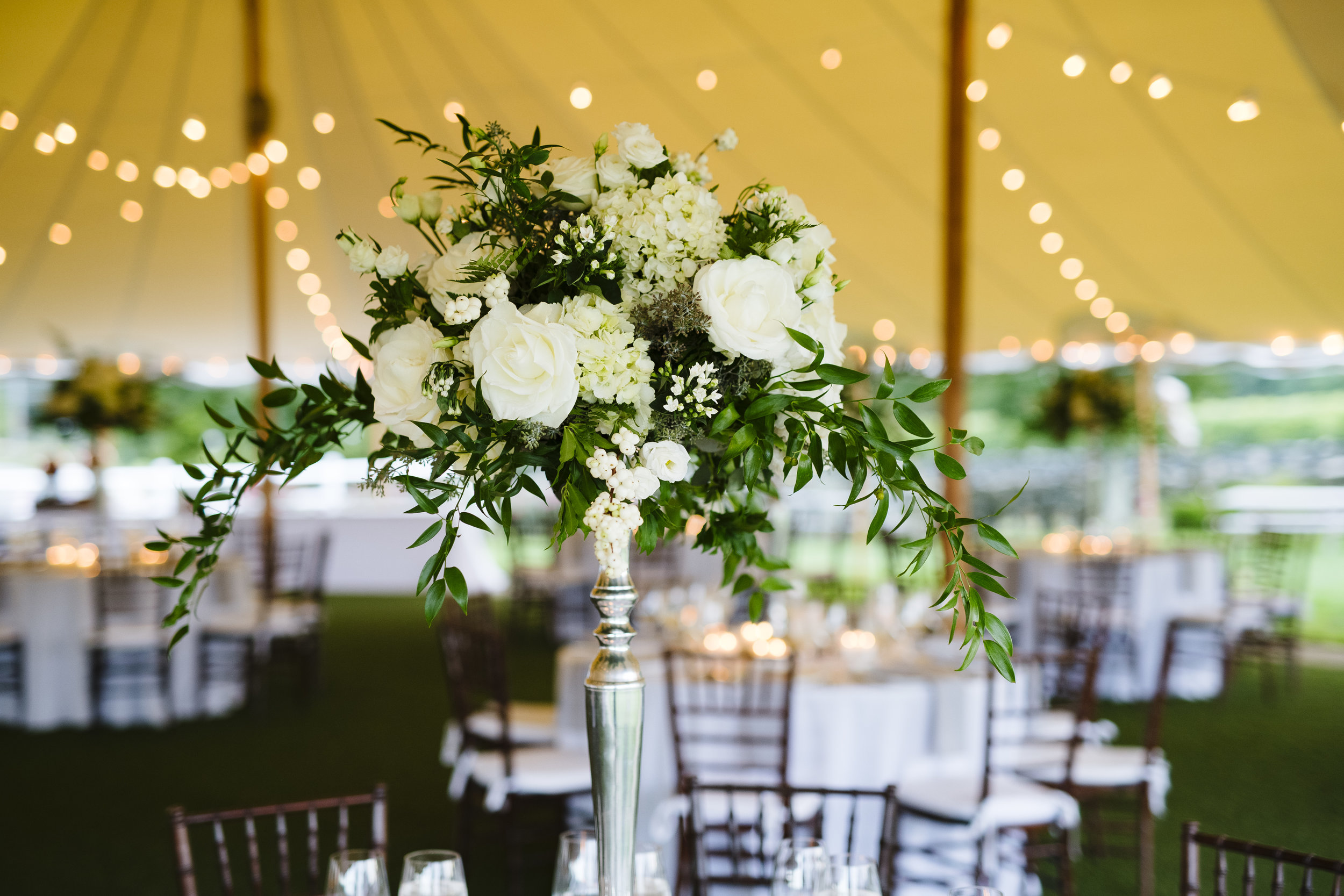 Tall white rose and greenery elegant but classy centerpieces under tent at Jonathan Edwards Winery in Connecticut - Pearl Weddings &amp; Event