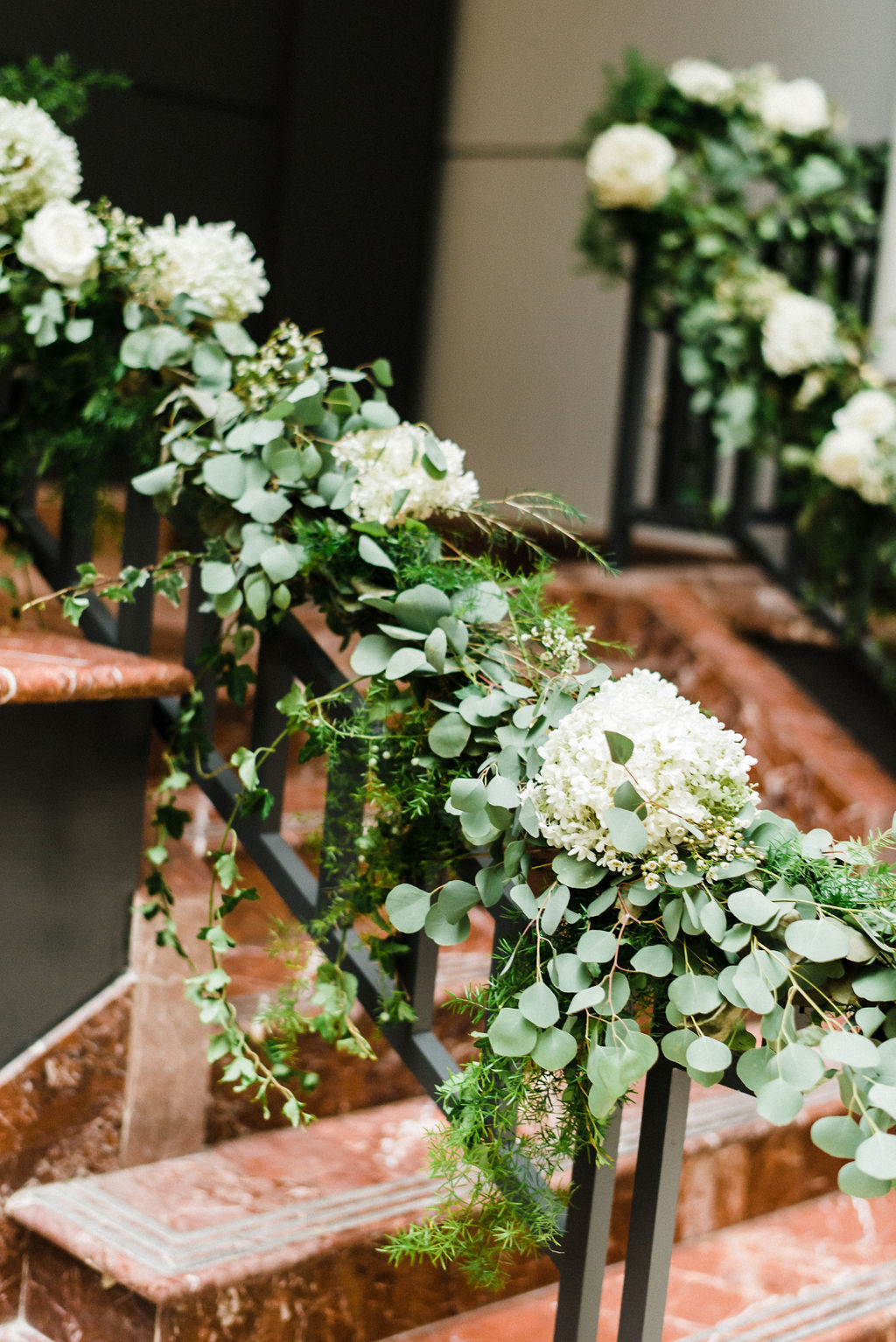 Hydrangeas, white roses and silver dollar eucalyptus cascading down the entrance staircase at The Goodwin Hotel - Pearl Weddings &amp; Events