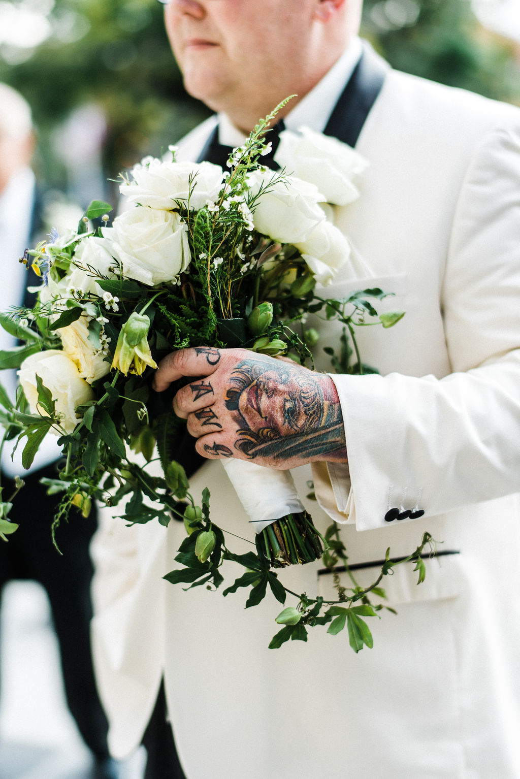 Tattoos and bridal bouquets have never looked so good! Groom, Tyler Anderson is in his all white Vera Wang suit holding his wife's bouquet by Ruth L. - Pearl Weddings &amp; Events