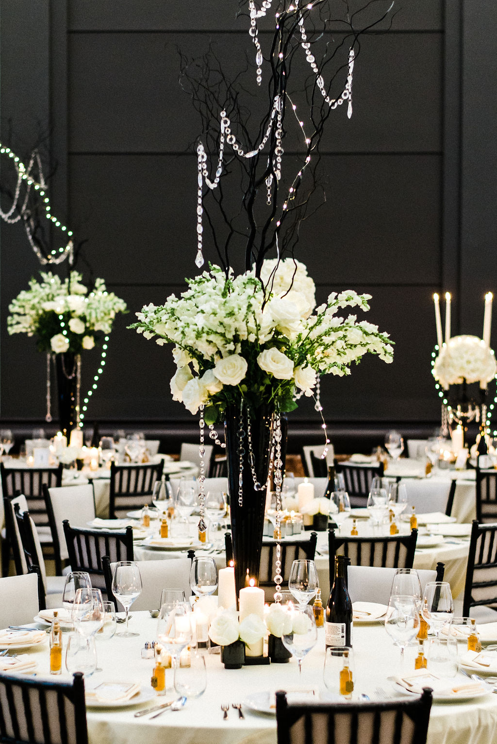 Tall black glass vases and white roses as the wedding centerpieces for a Great Gatsby themed wedding - Pearl Weddings &amp; Events