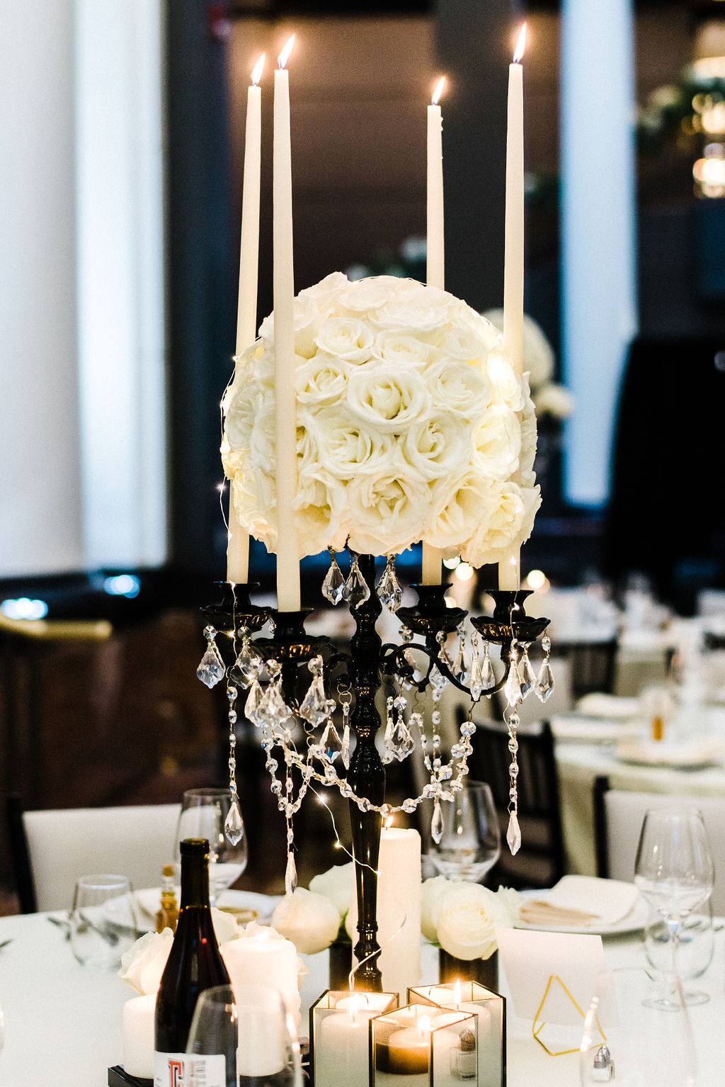 Floral centerpieces designed by Ruth L. White roses on a black candelabra with ivory candle stick and hanging jewels - Pearl Weddings &amp; Events