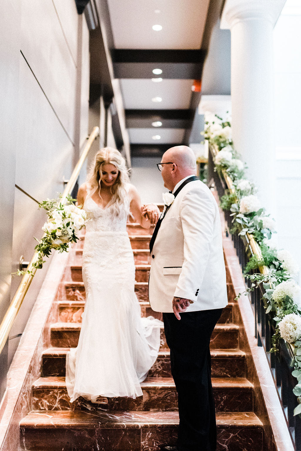 Tyler helps his new bride down the stairs at The Goodwin Hotel on their wedding day - Pearl Weddings &amp; Events