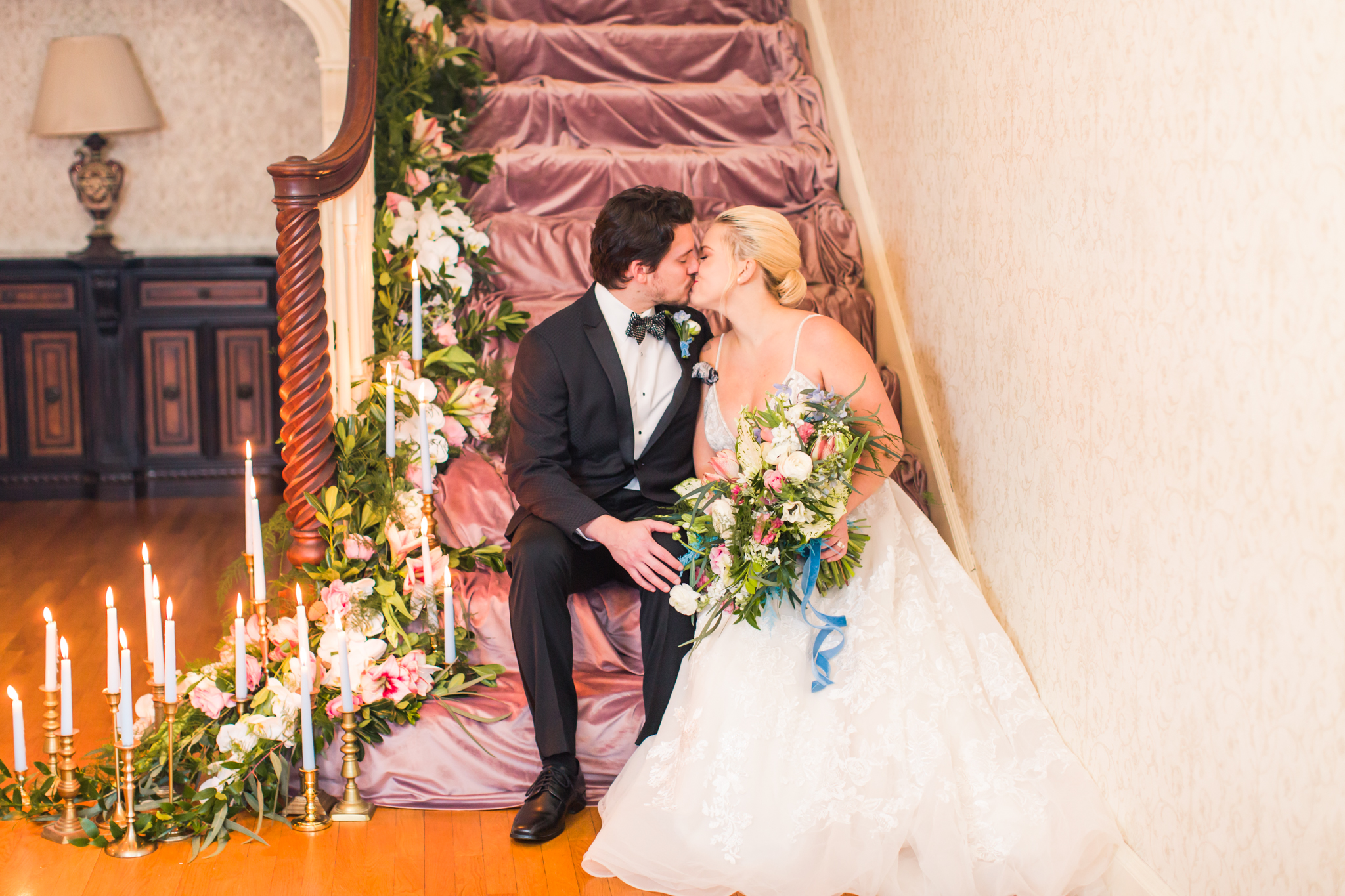 First kiss and first look one a pink velvet covered stair case covered in florals and candles - Pearl Weddings &amp; Events