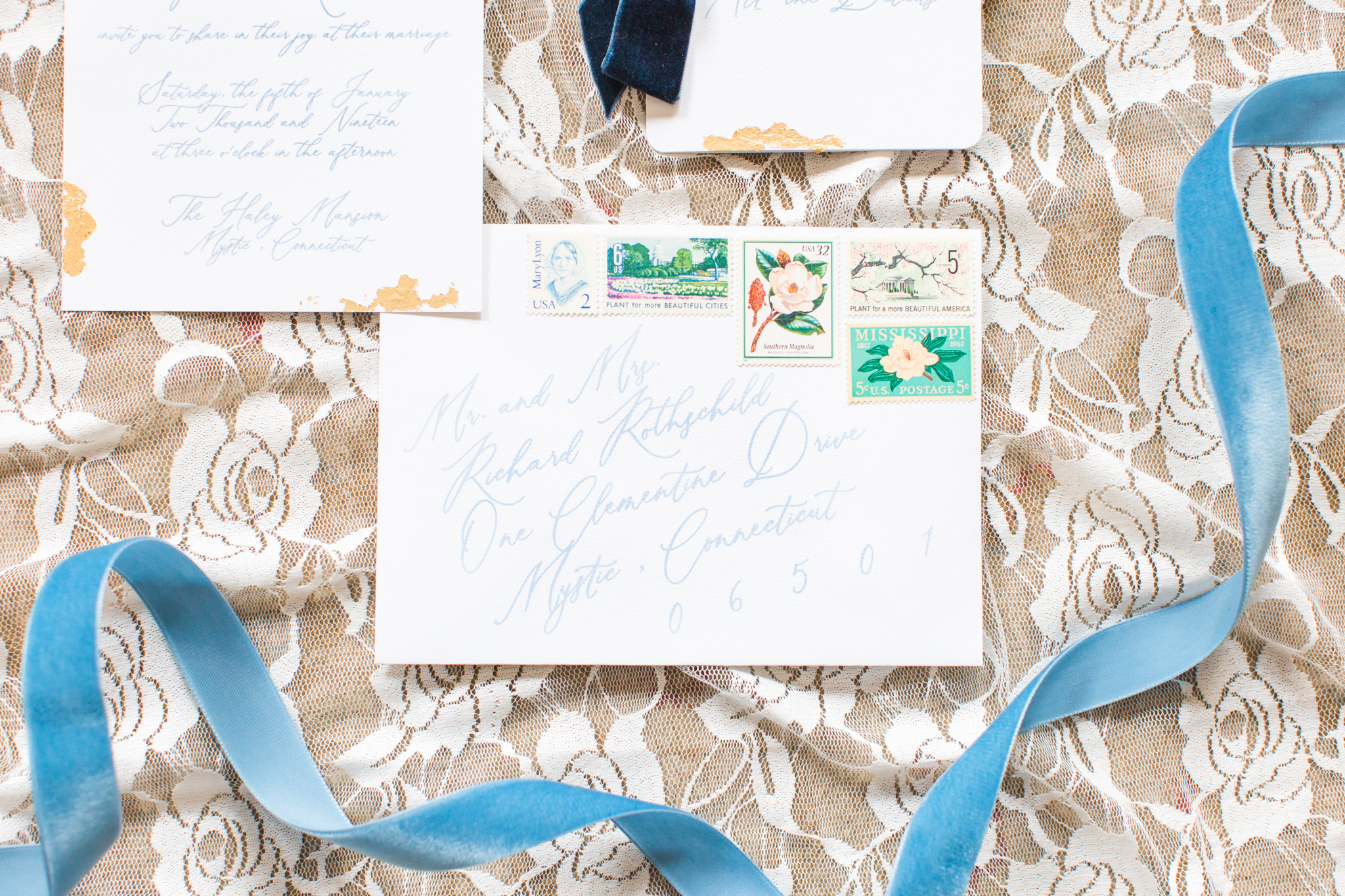 Invitation suite flat lays showcasing the vintage stamps, light blue fonts, gold leaf design for this elegant wedding - Pearl Weddings &amp; Events