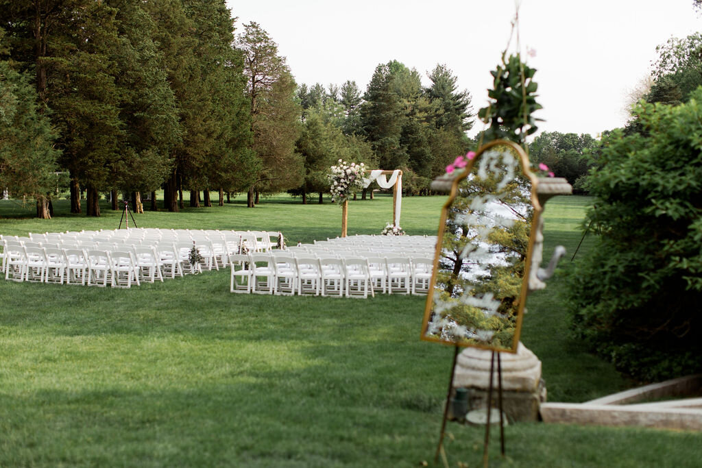 White garden chairs, mirror welcome sign and floral arch way - Pearl Weddings &amp; Events