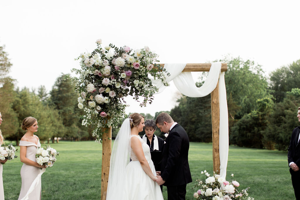 White, blush pink floral and green on wooden arch way with white fabric - Pearl Weddings and Events