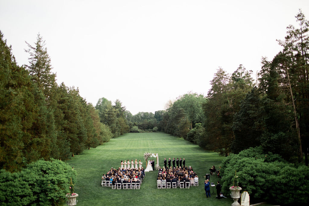 Ceremony with white chairs and wooden arch way - Pearl Weddings and Events