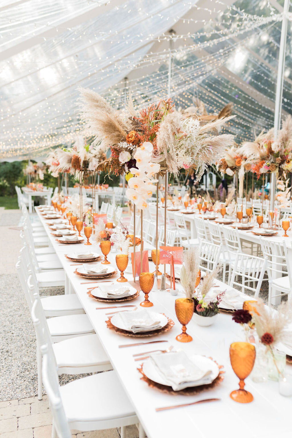 Sophisticated Boho white farm tables and chairs with amber glassware - Pearl Weddings &amp; Events