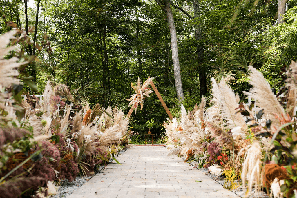 The isle is lined with rustic flowers and leads to the alter with a wooden triangular arch