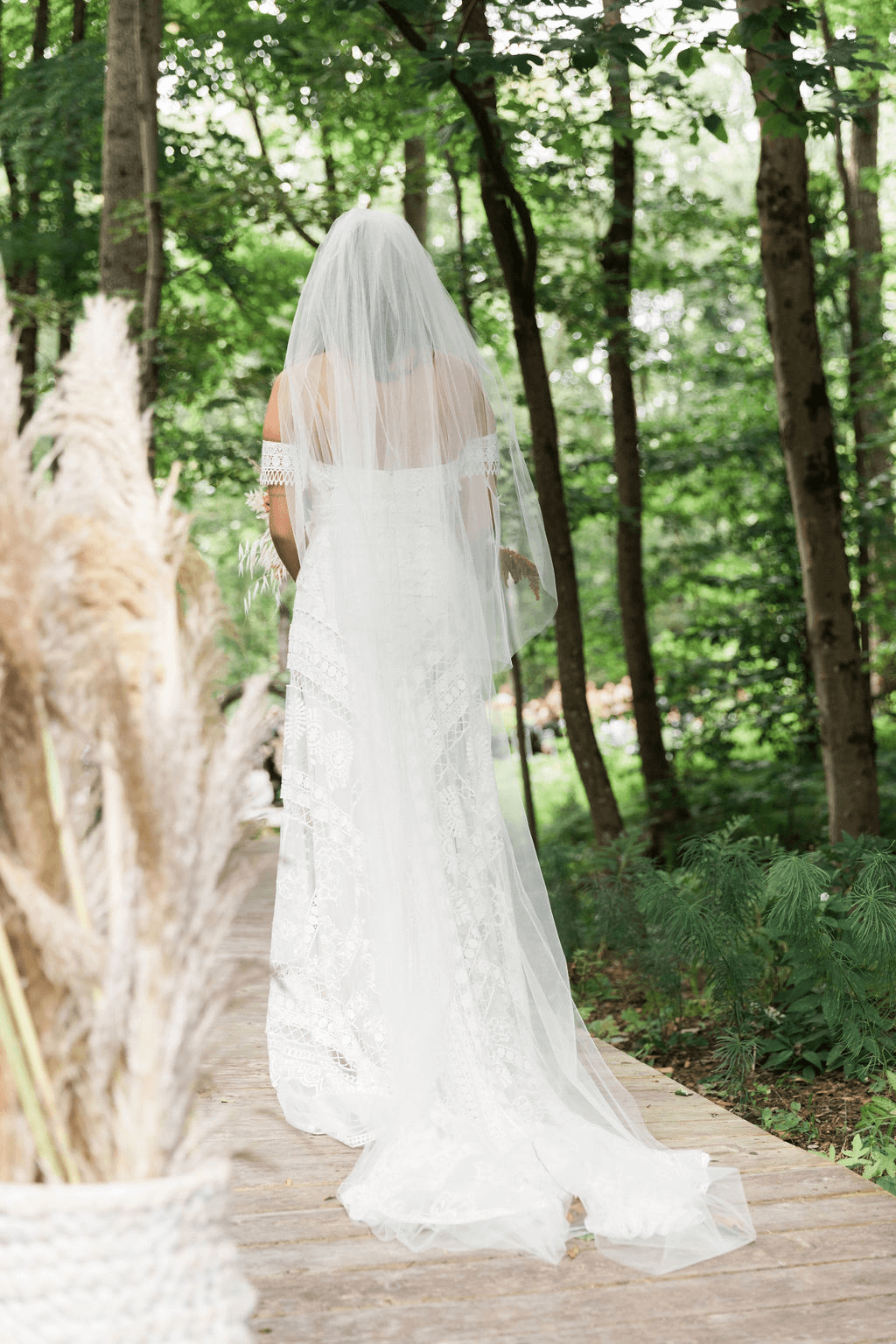 The bride, in her veil, walks back towards the camera