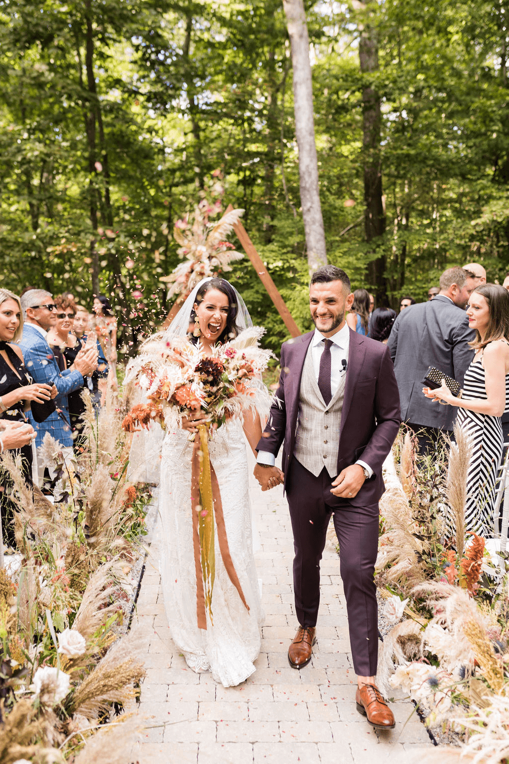Bride and groom walk down the isle hand in hand as guest throw confetti