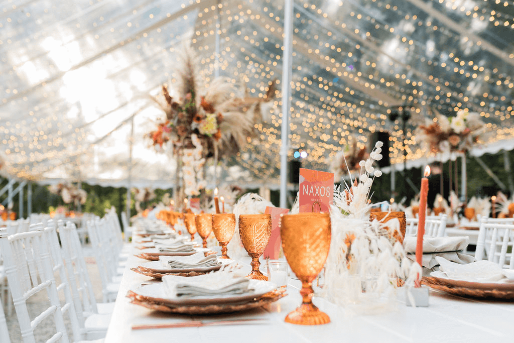 A close up table set up with amber glasses and sparkly lights in the background