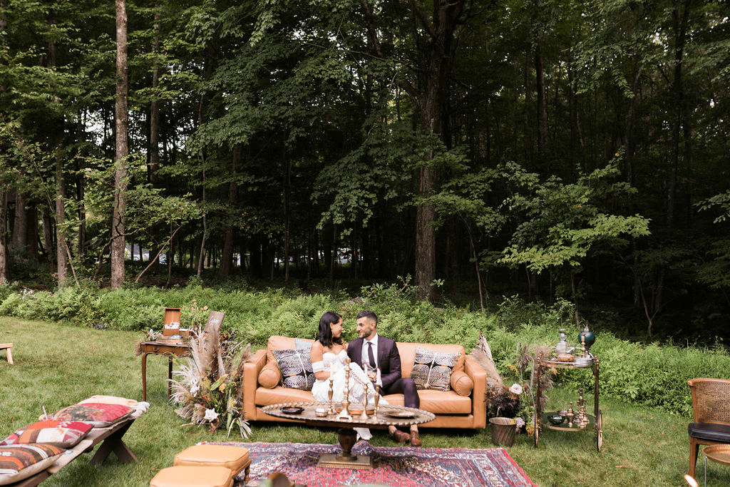 Bridge and groom sit together on a couch that is part of their wedding lounge
