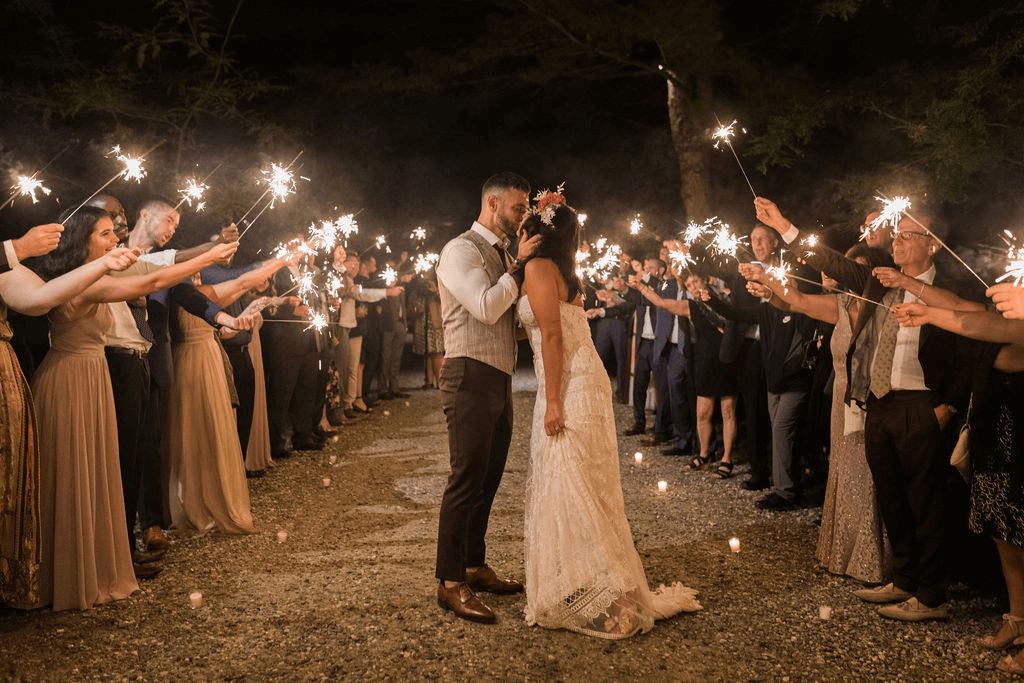Bride and groom kiss as guests hold up sparklers
