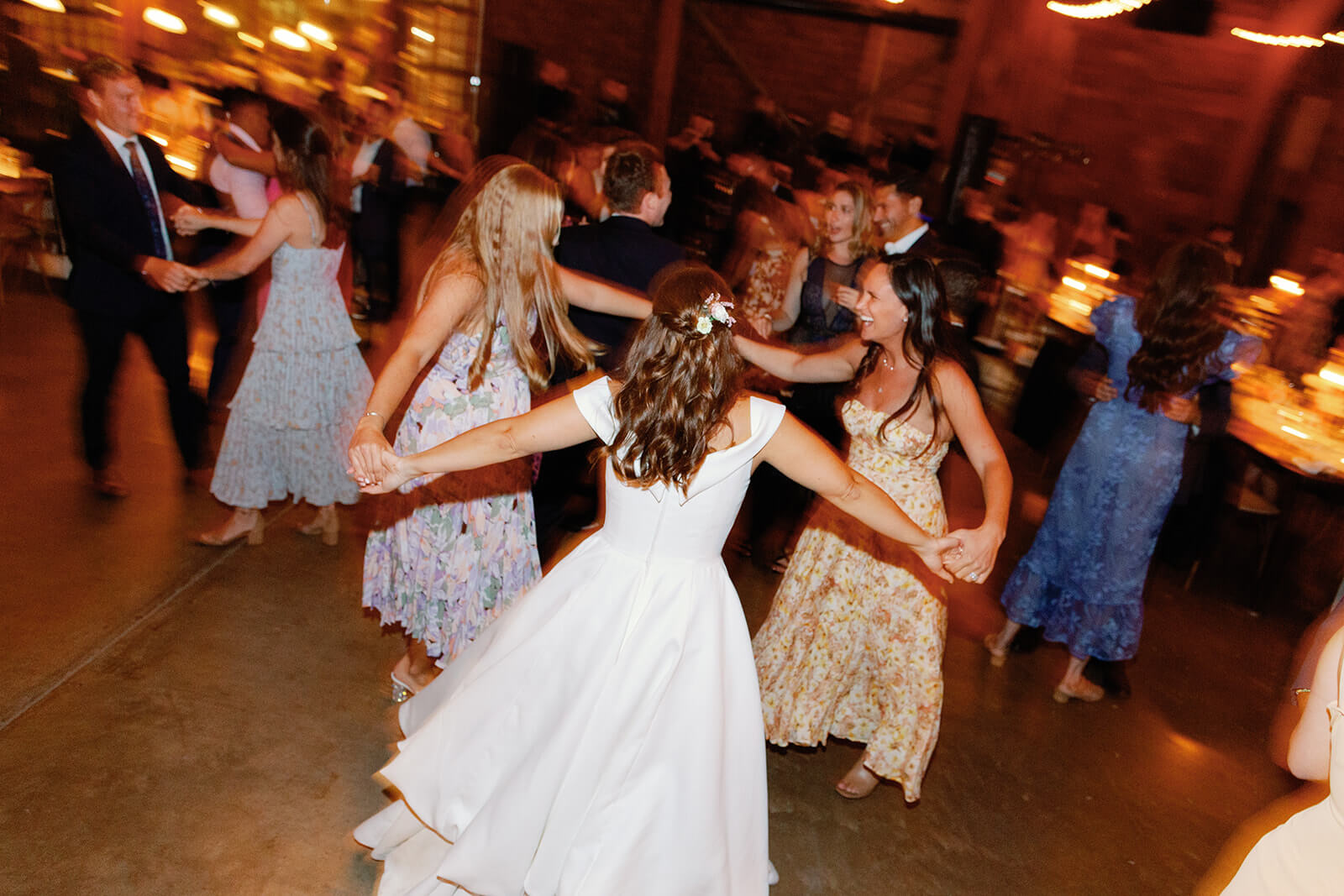 The bride holds hands with two friends as they dance