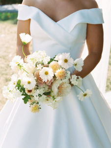 A close up of the brides bouquet as she holds it close to her wedding dress