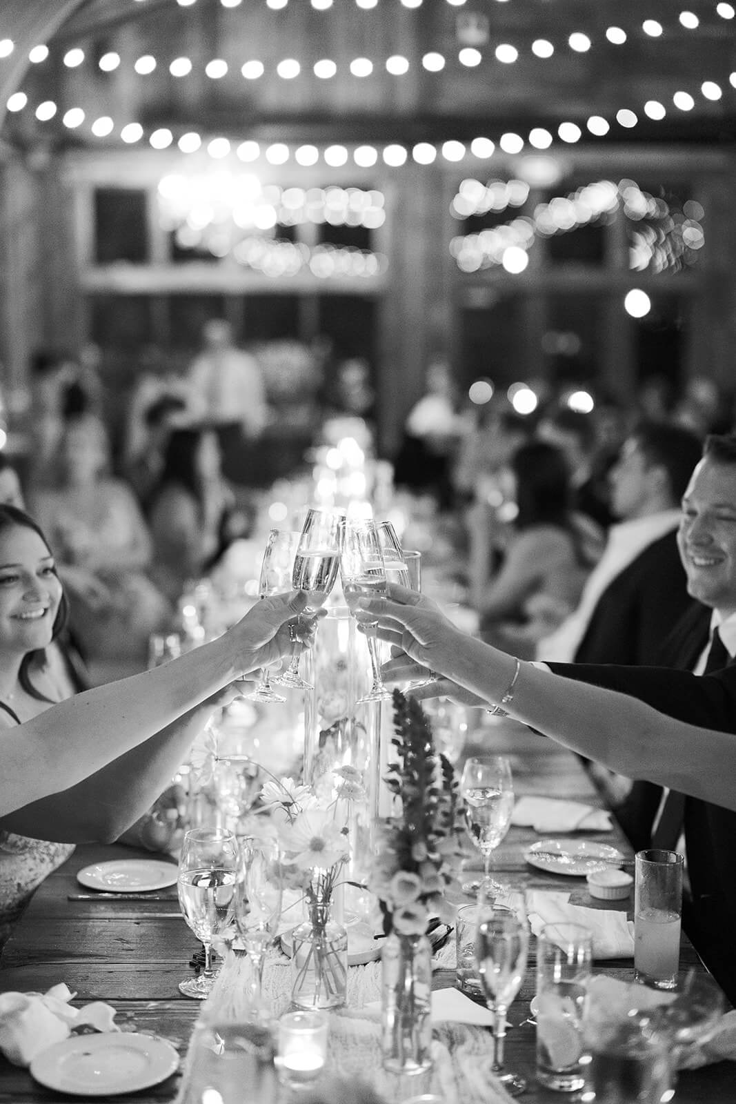 A black and white photos as people clink their glasses together in cheers