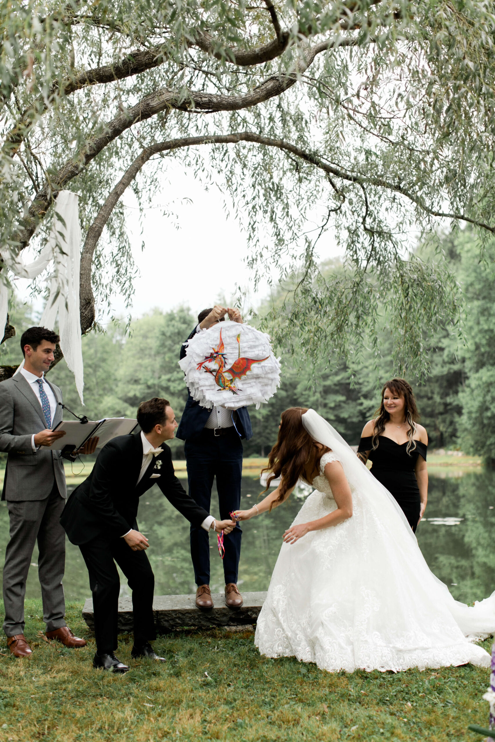 Bride and groom opening a pinata during the reception of their outdoor Connecticut wedding.