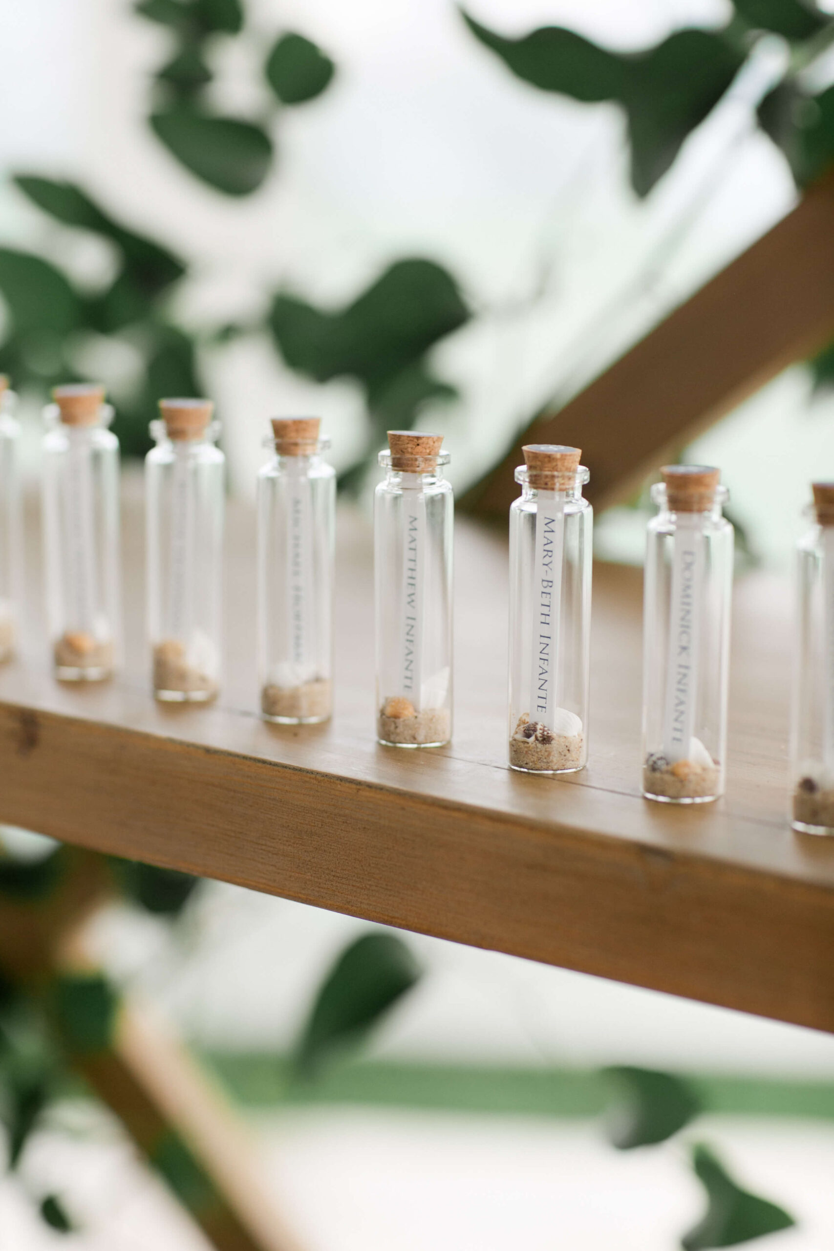 Seating chart with guests named in small bottles with shells and sand